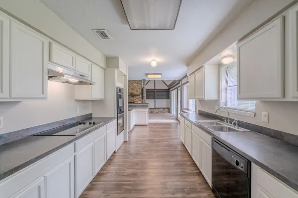 a kitchen with granite countertop white cabinets and stainless steel appliances