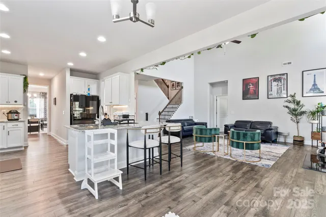 a living room with furniture a wooden floor and a kitchen