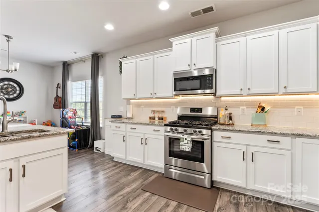 a kitchen with stainless steel appliances granite countertop a stove and white cabinets