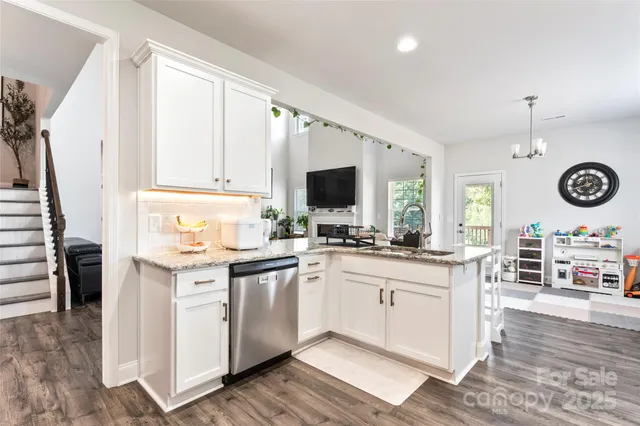 a kitchen with stainless steel appliances granite countertop a stove top oven a sink a dining table and chairs with wooden floor