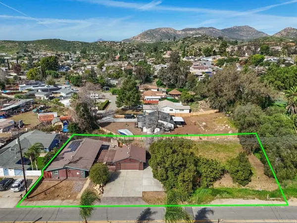 an aerial view of residential houses with outdoor space and trees