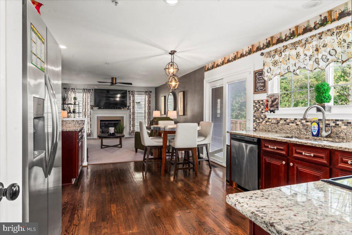 16308 Eddinger Road Bowie, MD 20716 - Photo 7 of 45 a open kitchen with stainless steel appliances granite countertop a refrigerator a stove top oven a dining table and chairs with wooden floor