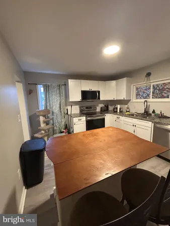 a large kitchen with stainless steel appliances a stove a refrigerator a sink dishwasher a dining table and chairs with wooden floor