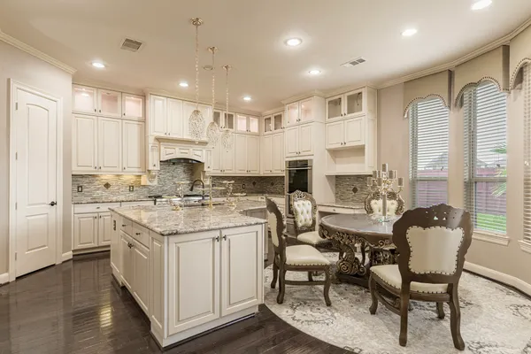 a kitchen with stainless steel appliances kitchen island granite countertop a dining table chairs and white cabinets