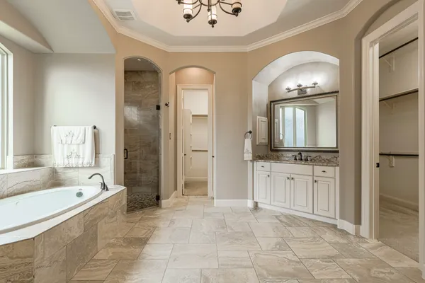 a spacious bathroom with a tub sink and mirror