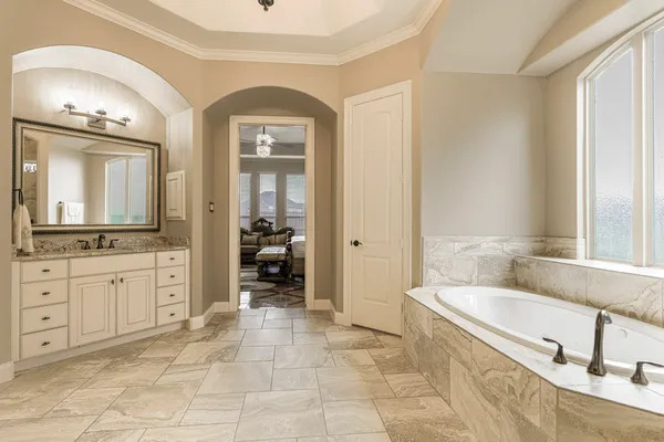 a spacious bathroom with a tub sink and mirror