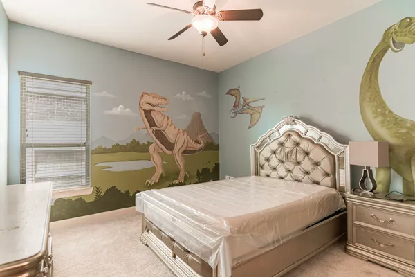 a bedroom with a bed a mirror on dresser and a chandelier