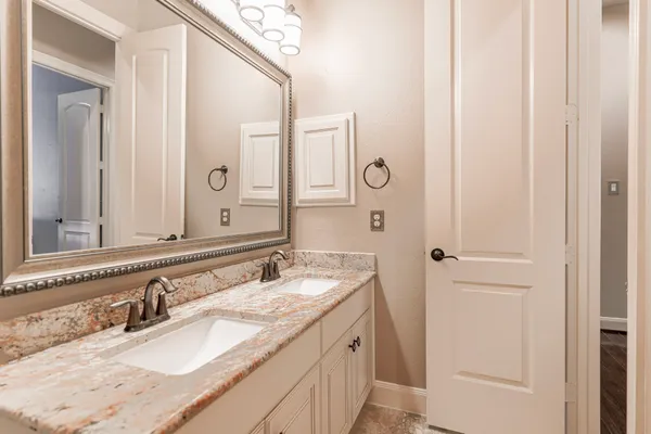 a bathroom with a granite countertop double vanity sink and a mirror