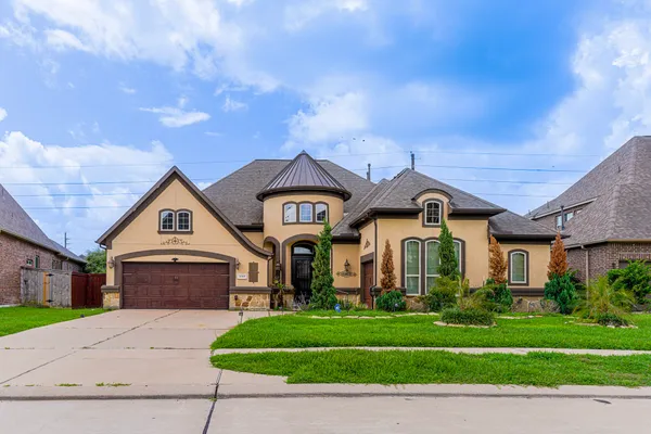 a front view of a house with a garden and trees