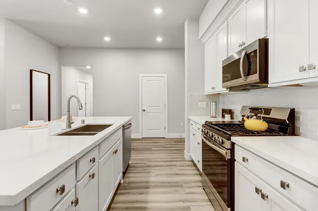 a kitchen with stainless steel appliances a stove a sink and a microwave