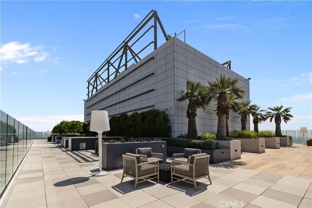 a view of a patio with couches table and chairs under an umbrella with potted plants