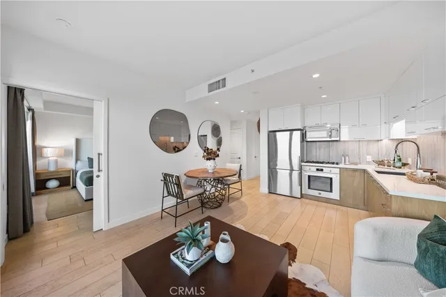 a living room with stainless steel appliances furniture a rug and a kitchen view