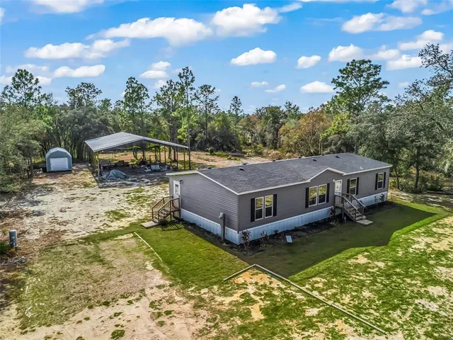 a aerial view of a house with swimming pool and trees in the background