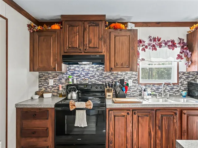a large kitchen with stainless steel appliances a stove a sink dishwasher and a refrigerator with wooden floor
