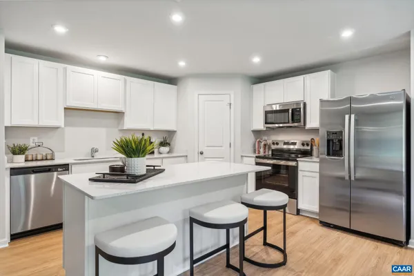 a living room with furniture kitchen view and wood floor