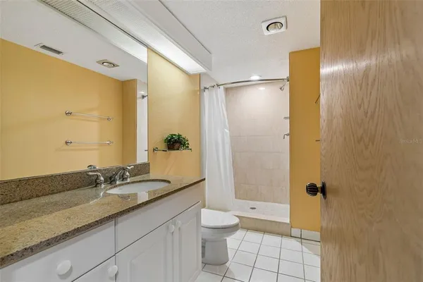 a bathroom with a granite countertop sink a toilet and shower