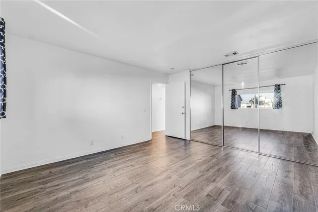 an empty room with wooden floor cabinet and windows