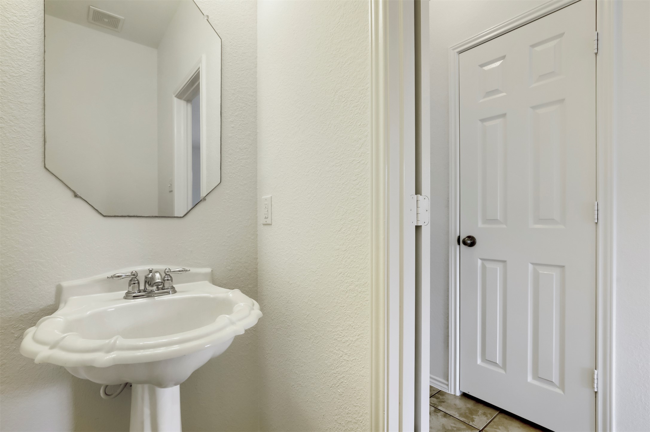 4125 Pebble Ridge Cove Round Rock, TX 78681 - Photo 13 of 30 A pristine pedestal sink paired with an octagonal mirror creates a clean, classic powder room.
