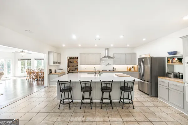 a large kitchen with kitchen island a island a sink a stove and a dining table with bookshelf