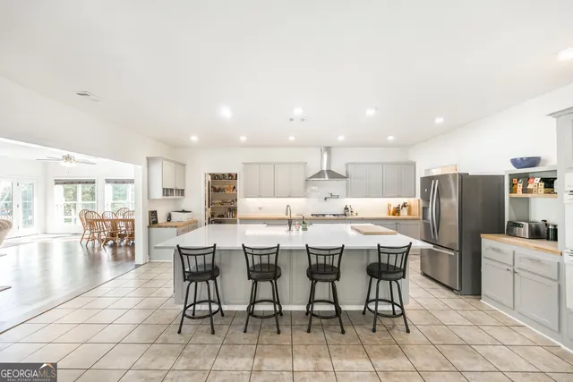 a large kitchen with kitchen island a island a sink a stove and a dining table with bookshelf