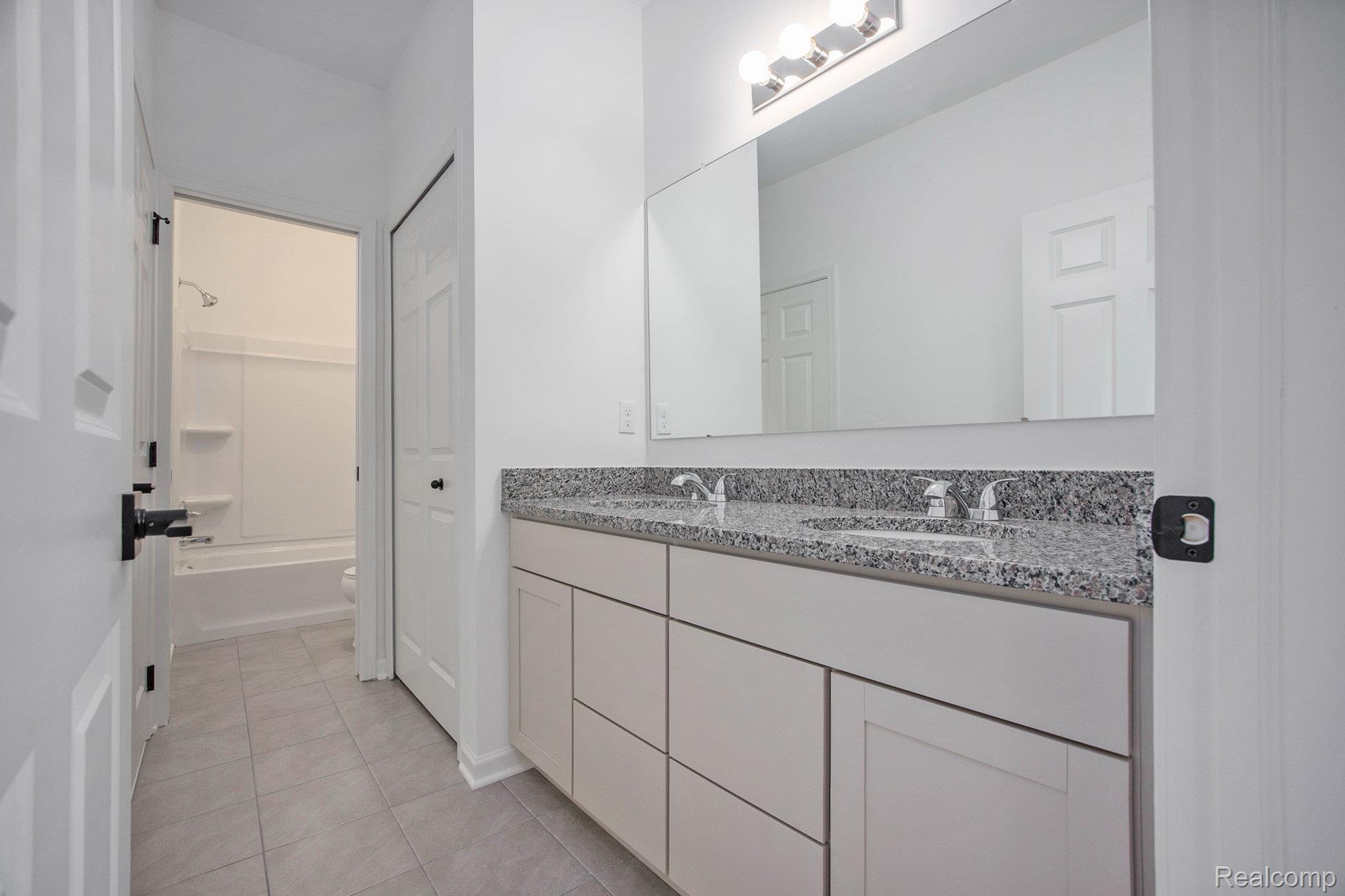 68788 Place Road New Haven, MI 48050 - Photo 10 of 29 Full bath with double vanity, light tile patterned floors, and washtub / shower combination
