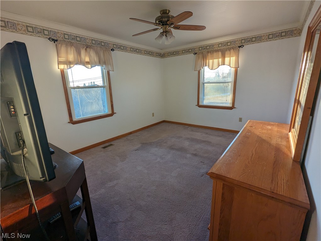 53154 Key Bellaire Road Bellaire, OH 43906 - Photo 14 of 43 Unfurnished bedroom featuring dark colored carpet, ceiling fan, multiple windows, and crown molding