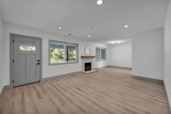 a view of an empty room with wooden floor fireplace and a window