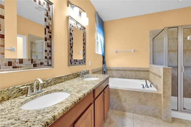 a bathroom with a granite countertop tub sink and mirror