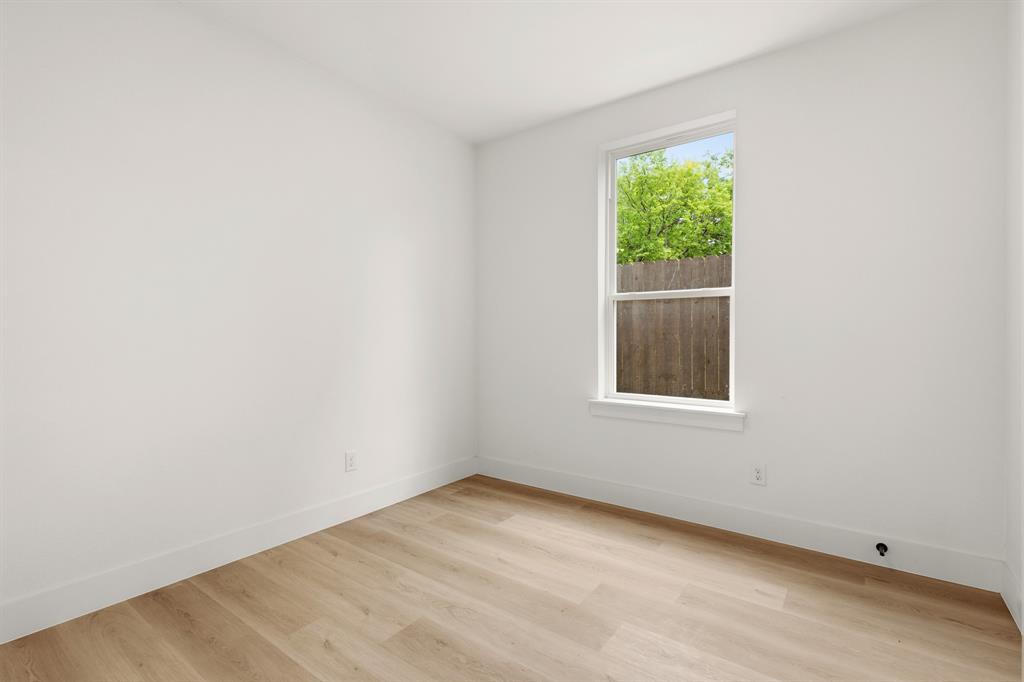 415 North Patton Avenue Dallas, TX 75203 - Photo 14 of 20 This room features light-toned wood flooring, clean white walls, and a window providing natural light and a view of exterior trees and a wooden fence
