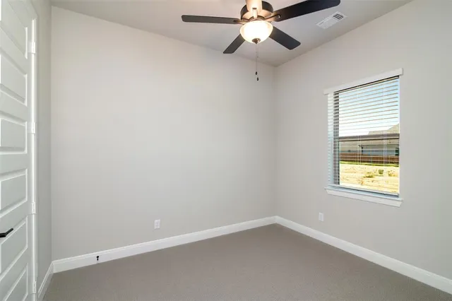 an empty room with a window and a fan
