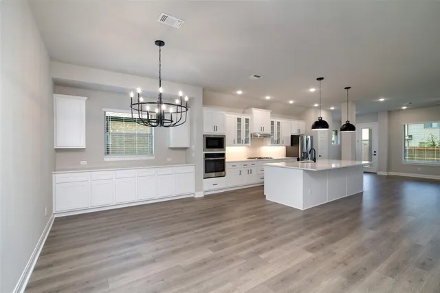 a view of large kitchen with kitchen island a stove a sink dishwasher and a fireplace with wooden floor