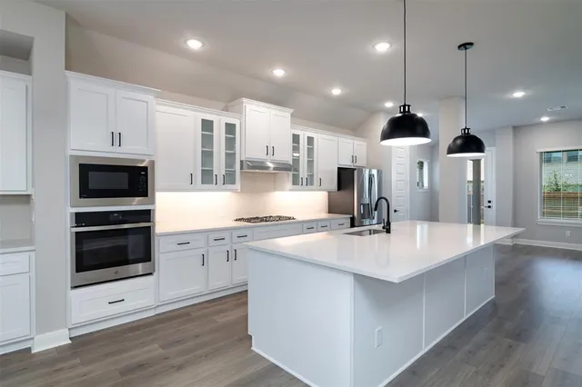a large kitchen with stainless steel appliances and white cabinets