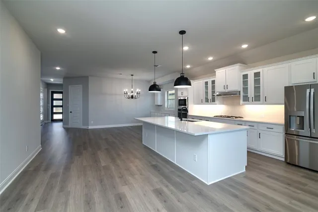 a large kitchen with stainless steel appliances kitchen island granite countertop a large counter top and wooden floors