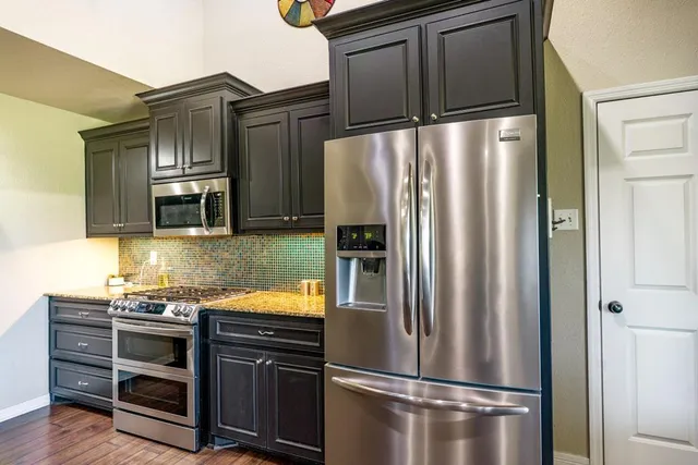 a kitchen with stainless steel appliances granite countertop a refrigerator and a stove top oven