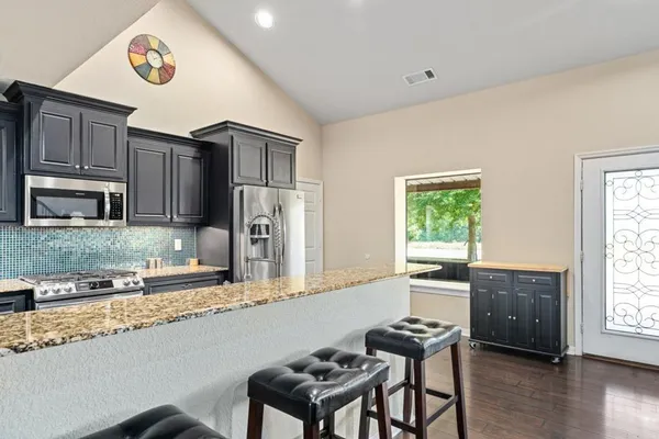 a kitchen with granite countertop a stove top oven a sink and cabinets