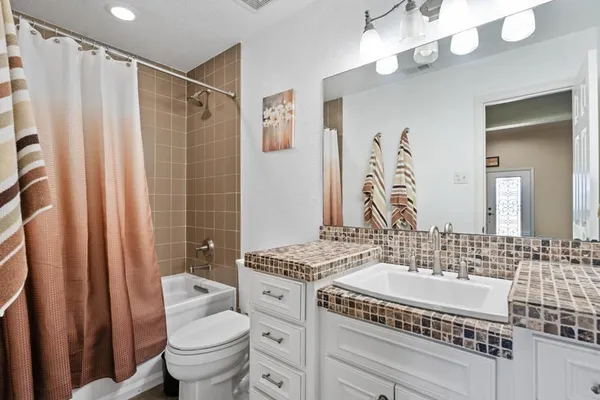 a bathroom with a sink a toilet a mirror a vanity and shower