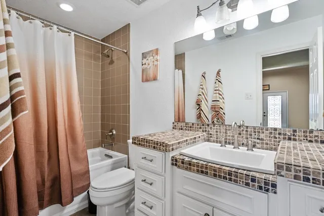 a bathroom with a sink a toilet a mirror a vanity and shower