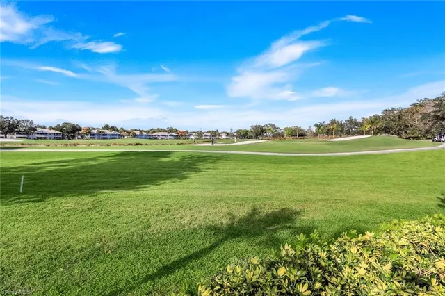 a view of a big yard with lots of green space and houses in the back