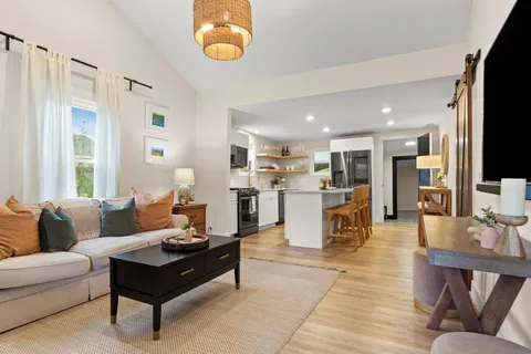 a living room with furniture kitchen view and a large window