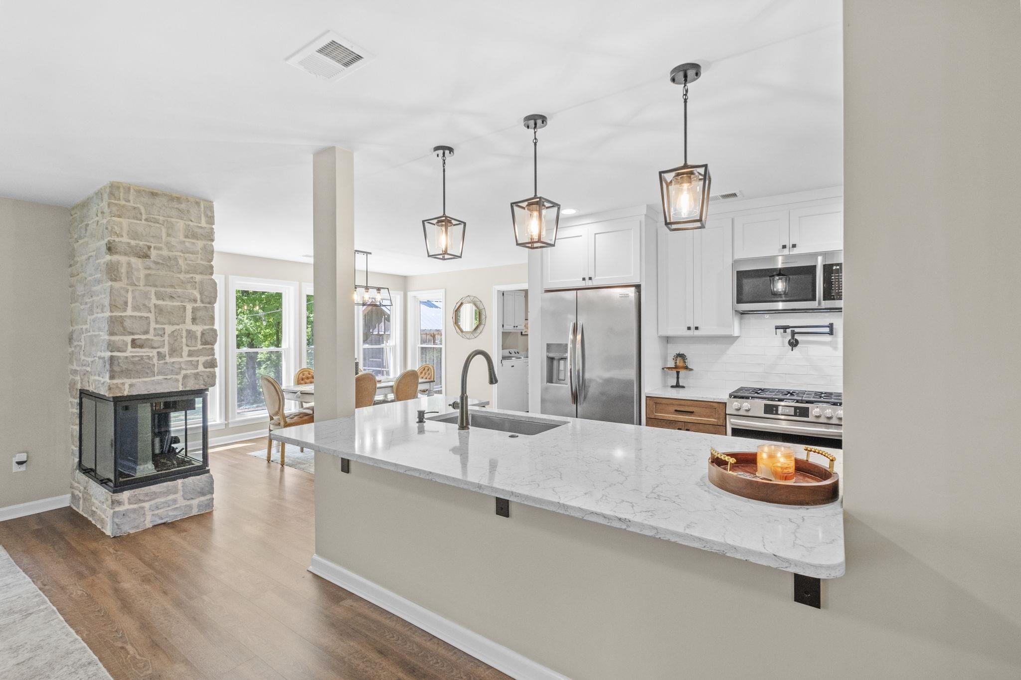 650 Firetower Road Somerville, TN 38068 - Photo 10 of 39 Kitchen featuring light stone countertops, white cabinetry, stainless steel appliances, decorative backsplash, and a kitchen breakfast bar