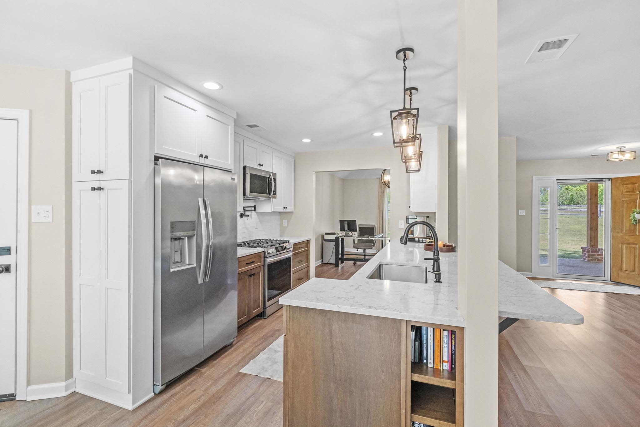 650 Firetower Road Somerville, TN 38068 - Photo 11 of 39 Kitchen featuring light stone counters, stainless steel appliances, a peninsula, light wood-type flooring, and two tone cabinetry