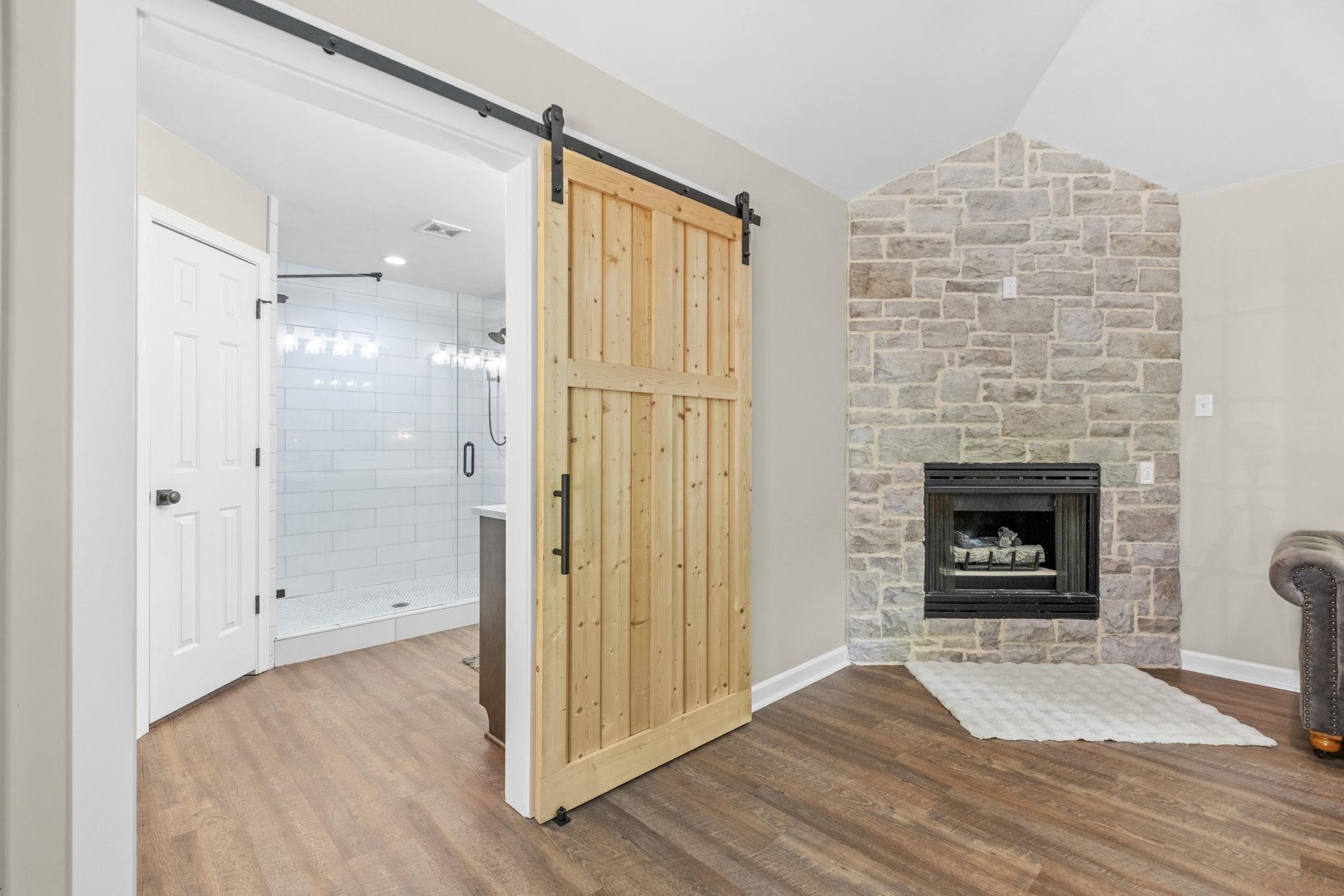 650 Firetower Road Somerville, TN 38068 - Photo 19 of 39 Unfurnished living room with dark wood-style floors, a stone fireplace, vaulted ceiling, and a barn door