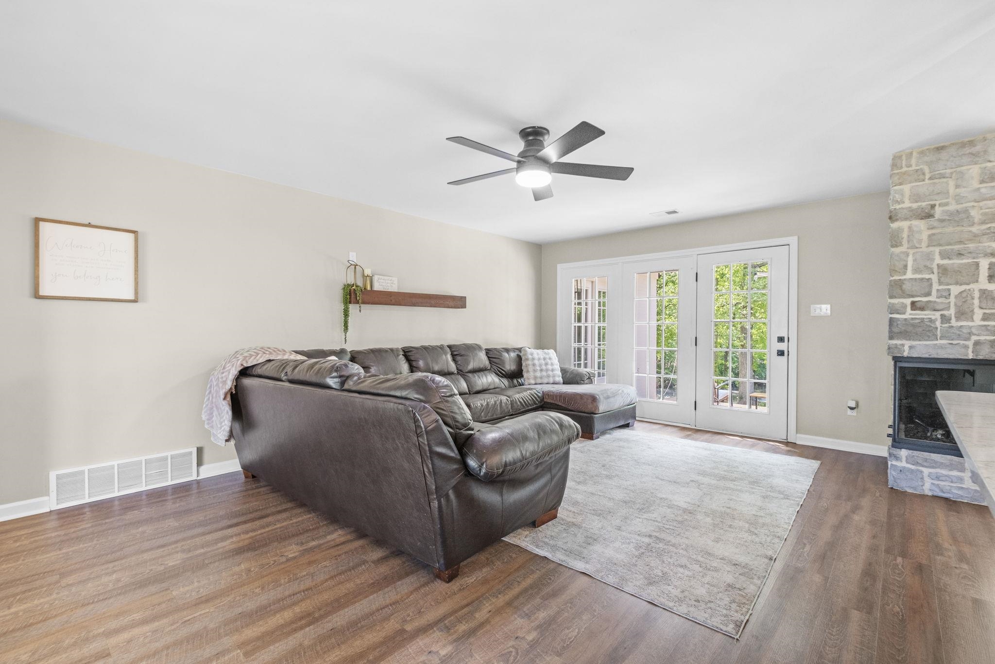 650 Firetower Road Somerville, TN 38068 - Photo 3 of 39 Living area featuring a stone fireplace, ceiling fan, and wood finished floors