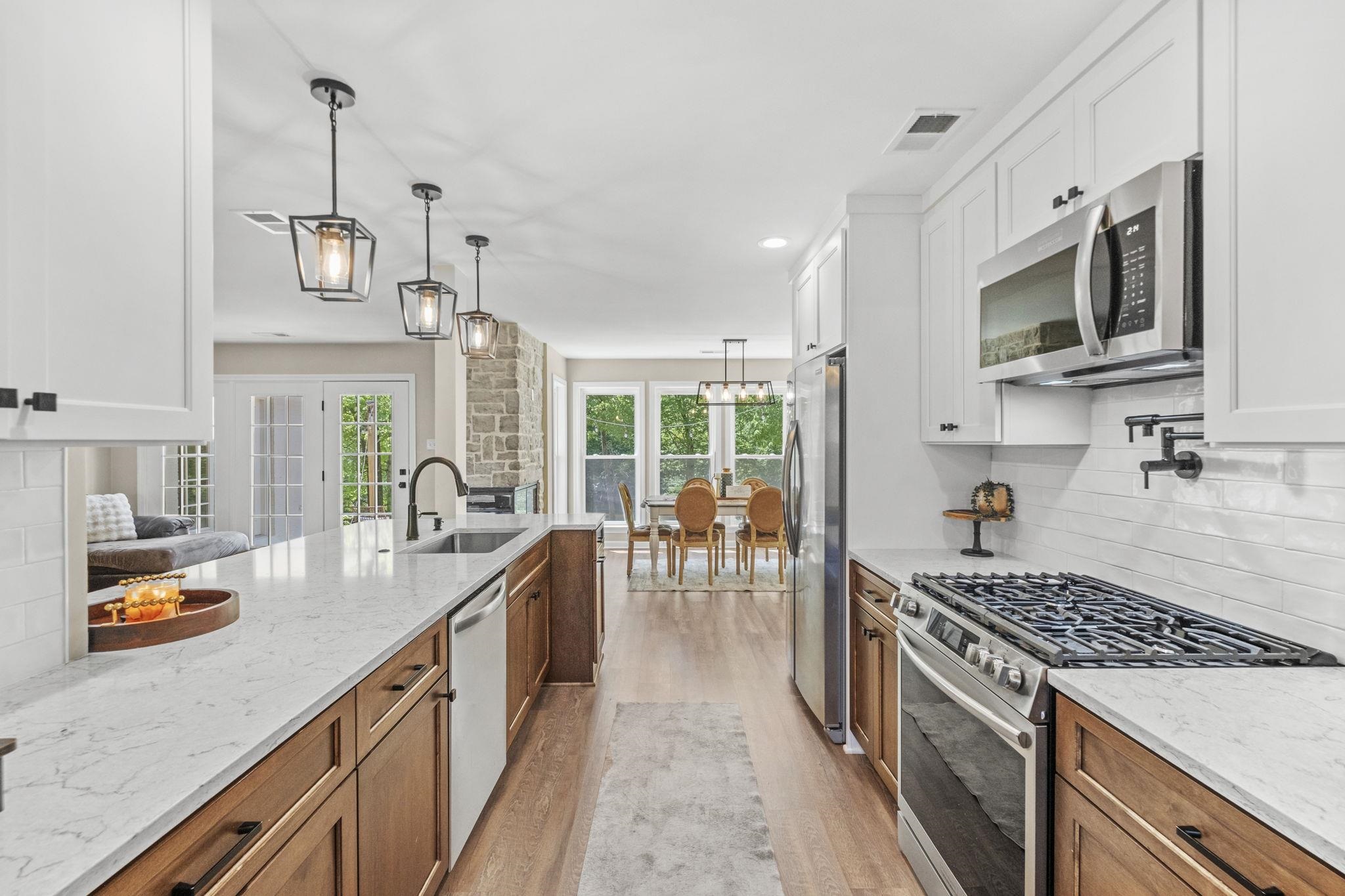 650 Firetower Road Somerville, TN 38068 - Photo 6 of 39 Dual tone kitchen with stainless steel appliances, backsplash, light stone countertops, light wood-style flooring, and dual tone cabinetry