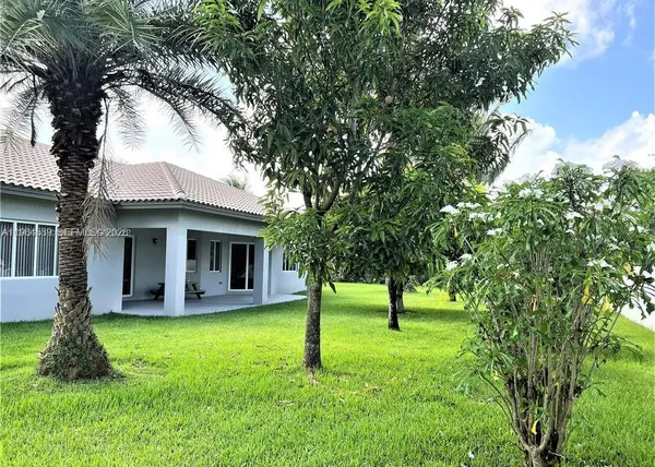 a view of a house with a yard and a large tree