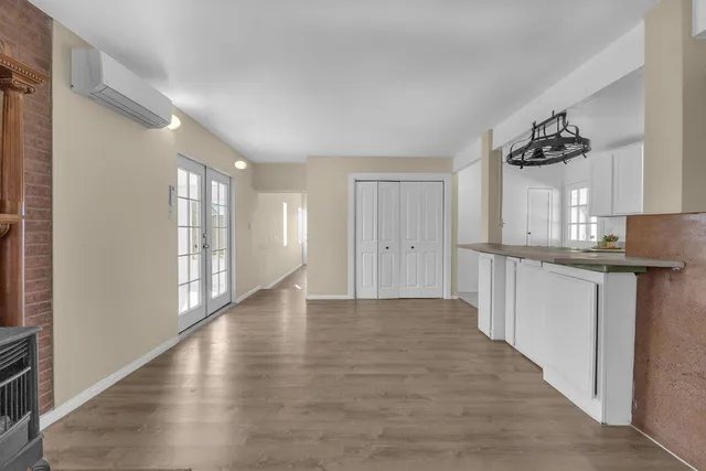 an empty room with wooden floor fireplace and windows