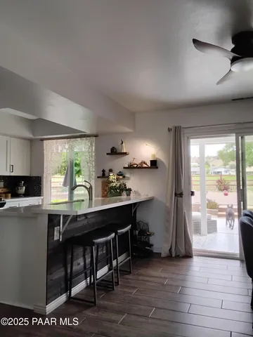a kitchen with stainless steel appliances kitchen island granite countertop a stove a sink dishwasher and a dining table with the living room view