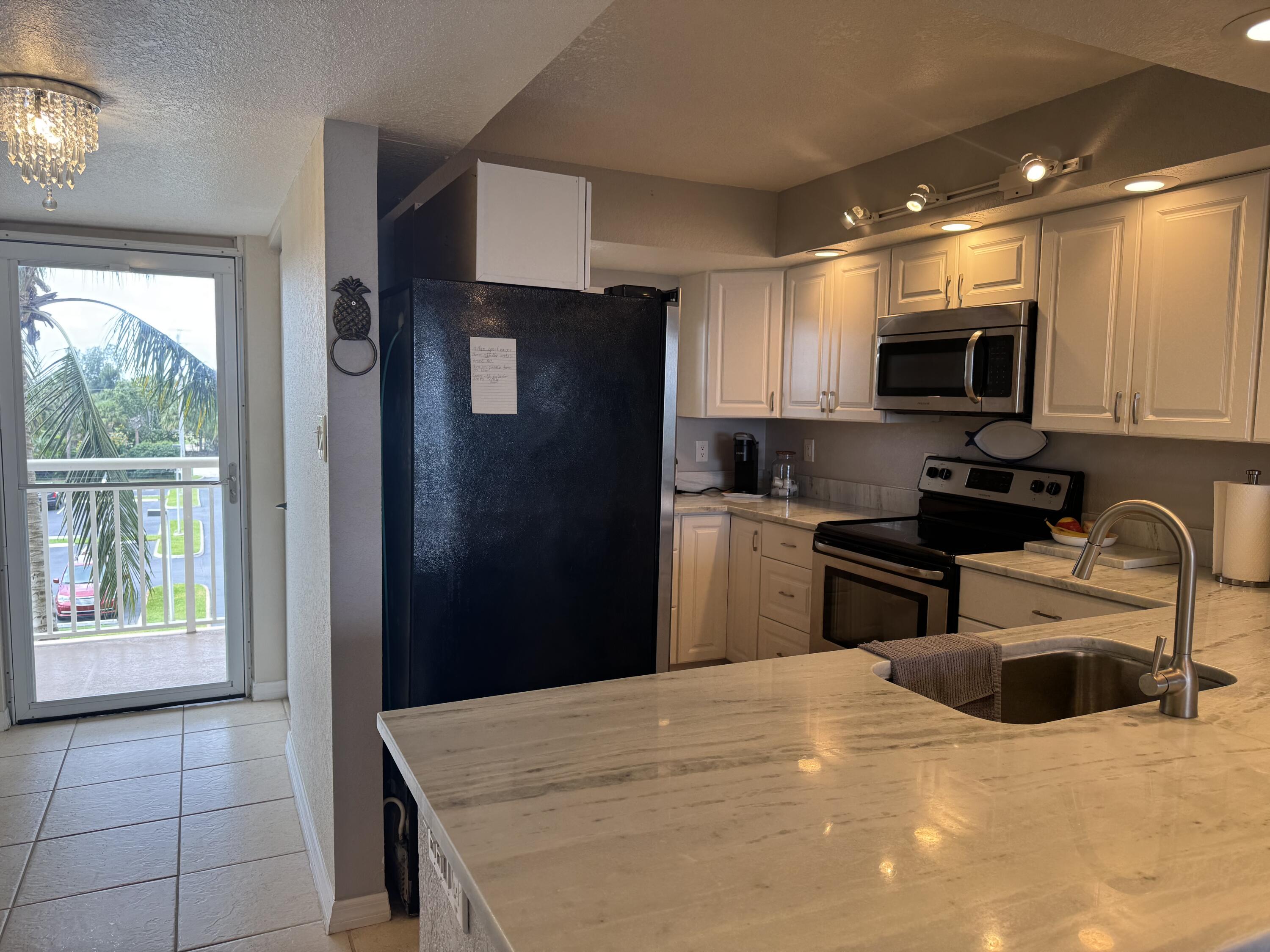 3200 North Hwy A1A, Unit 307 Hutchinson Island, FL 34949 - Photo 26 of 47 a kitchen with granite countertop a refrigerator and a sink