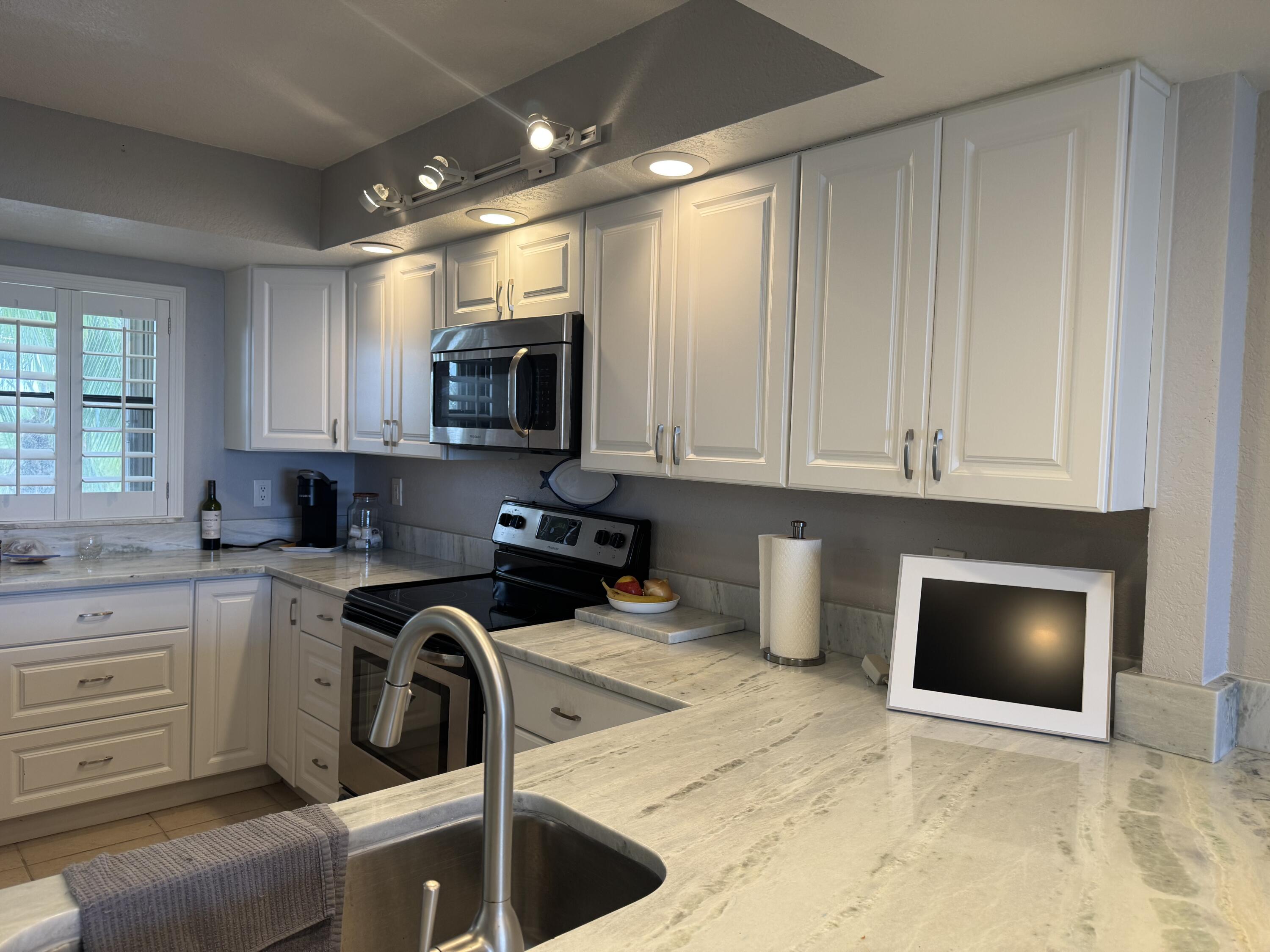 3200 North Hwy A1A, Unit 307 Hutchinson Island, FL 34949 - Photo 28 of 47 a kitchen with stainless steel appliances granite countertop a stove a sink and a microwave