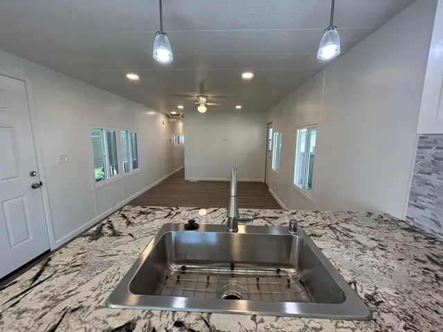 a kitchen with kitchen island granite countertop a sink and a stove